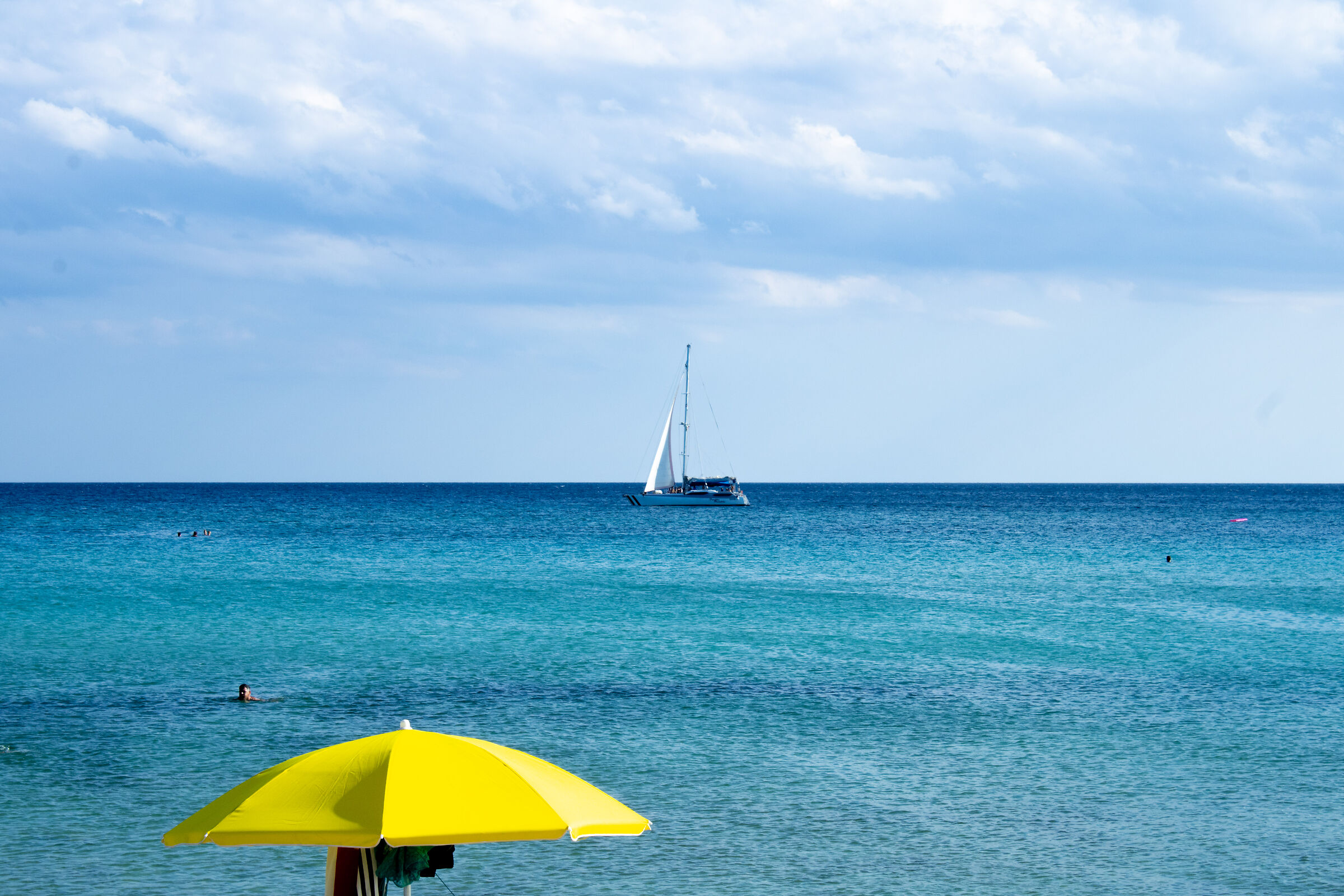 Sea with sailboat and yellow umbrella...