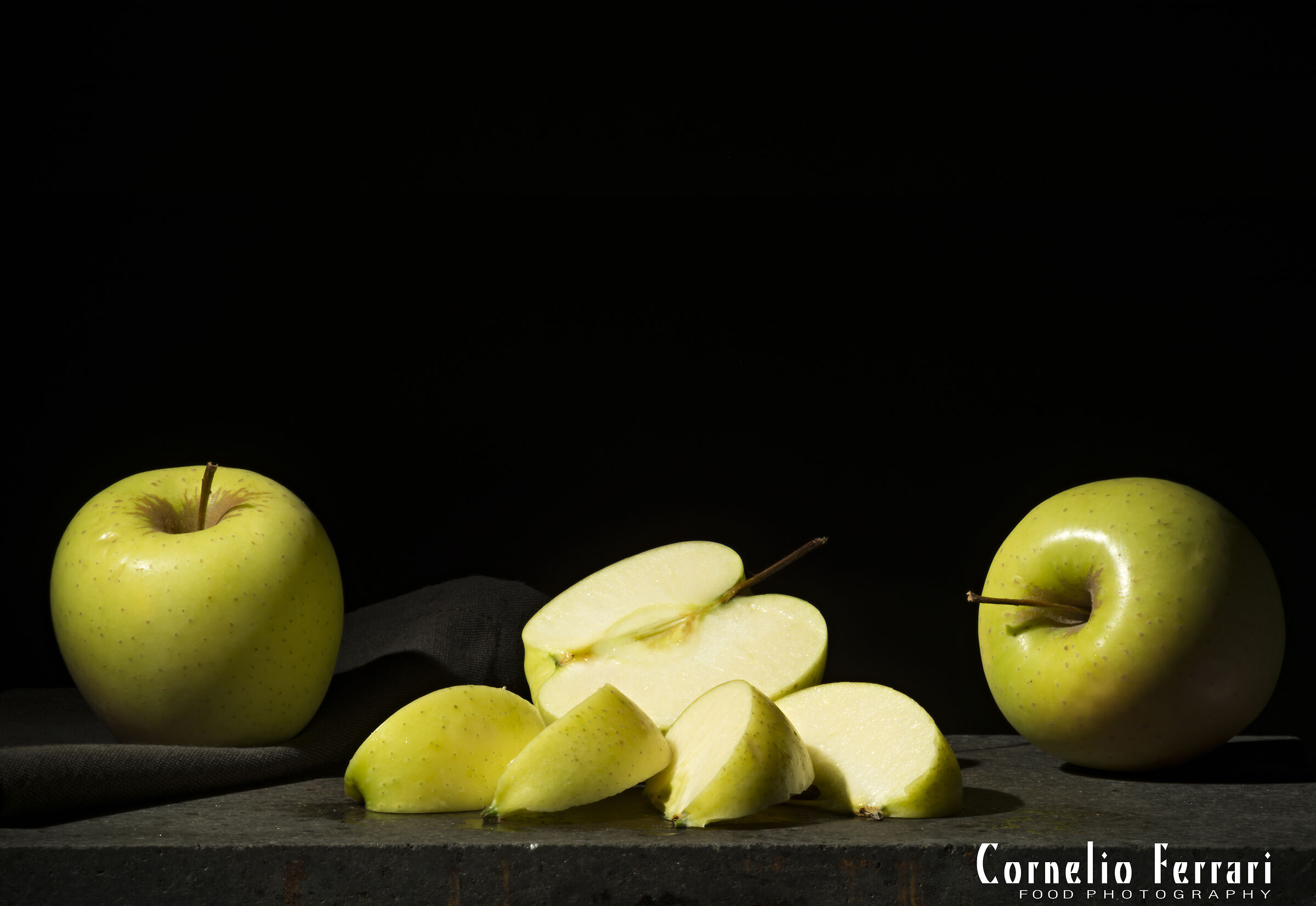 apples, cut into wedges on a black background ...